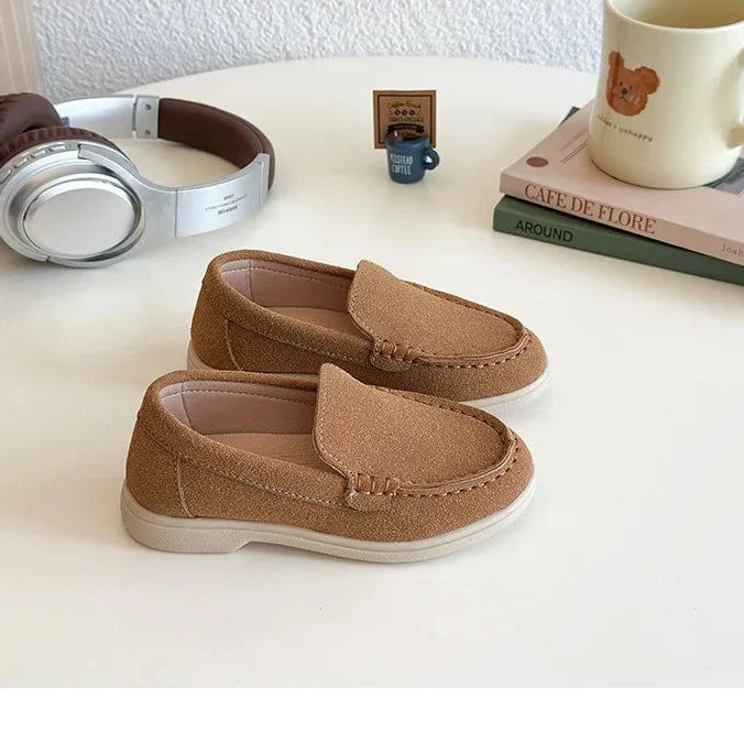 les deux mocassins marron vus de profil sur une table blanche