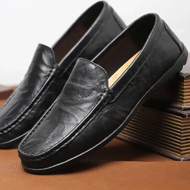 Mocassins noirs en cuir présentés inclinés contre deux livres