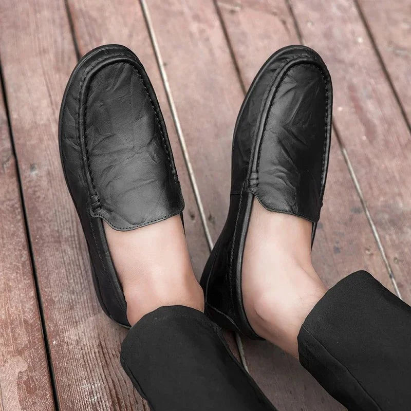 Paire de mocassins noirs portée vue du dessus sur un sol en bois
