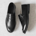deux mocassins noirs vus de dessus sur un sol clair