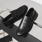 paire de mocassins noirs posée sur une chaise en métal