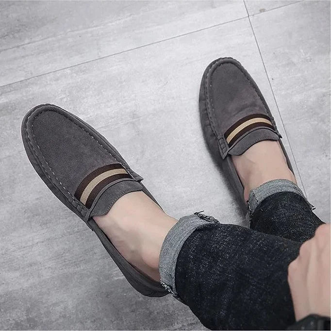paire de mocassins gris portée avec un jean retourné sur sol clair