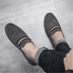 paire de mocassins gris portée avec un jean retourné sur sol clair