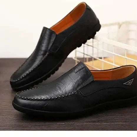 Deux mocassins noirs posés côte à côte sur une table, ambiance intérieure