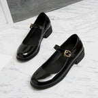 paire de mocassins vernis noirs posée au sol, vue diagonale