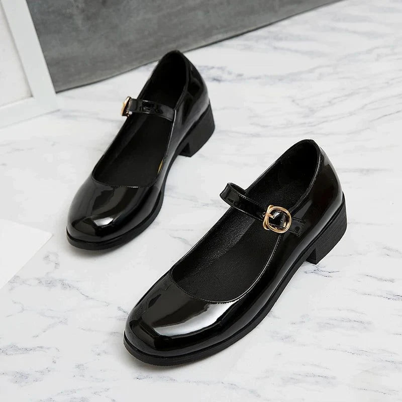 paire de mocassins vernis noirs posée au sol, vue diagonale