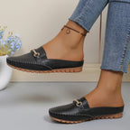 mules noires portées, jambe croisée, vue de profil