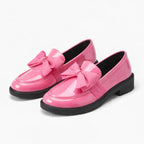 paire de mocassins à noeud en coloris rose à semelle noire posée sur fond clair