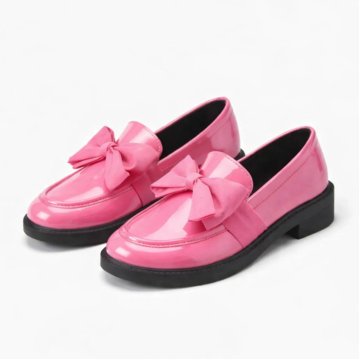 paire de mocassins à noeud en coloris rose à semelle noire posée sur fond clair