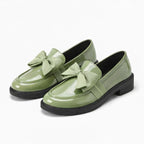 paire de mocassins à noeud en coloris vert sauge posée sur fond clair