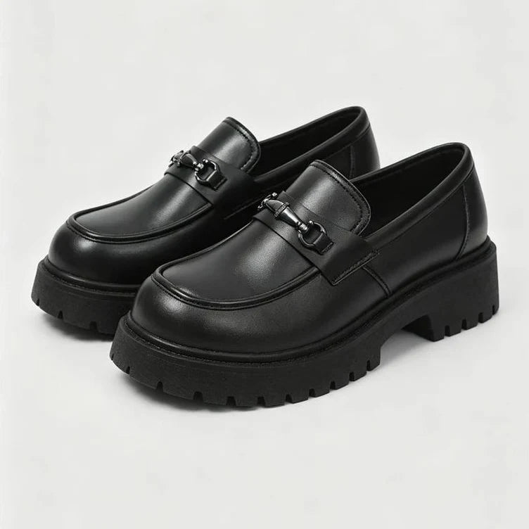 paire de mocassins noirs à plateforme vue de trois quarts sur fond clair
