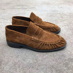 Mocassins en suédine marron présentés de côté sur une surface extérieure
