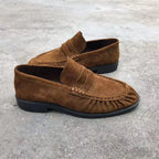 Vue de trois quarts des mocassins en suédine marron posés sur sol gris