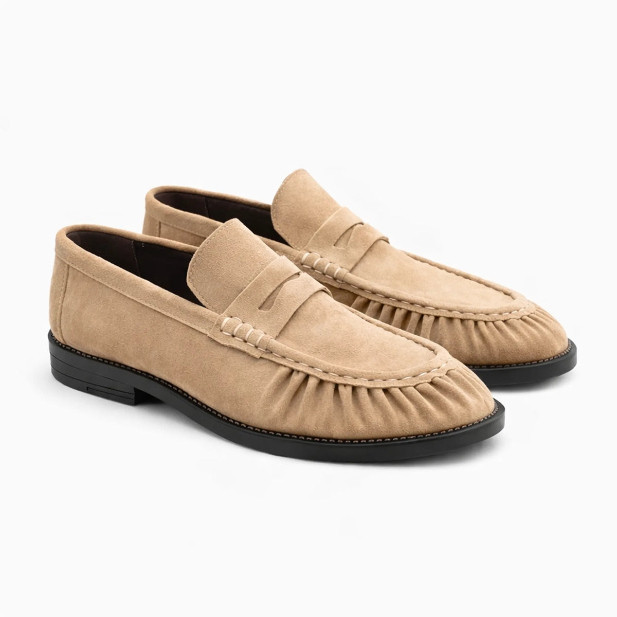 Mocassins en suédine coloris beige exposés sur fond uni clair