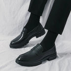 paire de mocassins vernis noirs portée, jambes croisées, fond clair