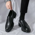 mocassins vernis noirs portés avec pantalon noir, une chaussure tenue à la main