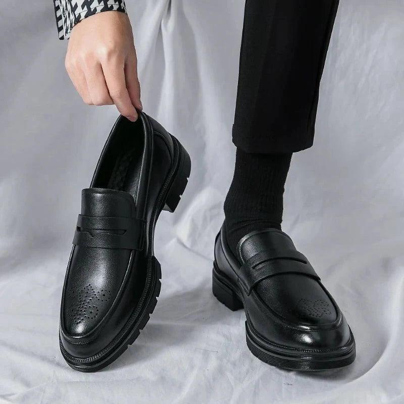 mocassins vernis noirs portés avec pantalon noir, une chaussure tenue à la main