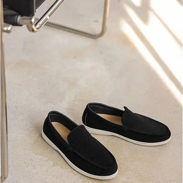 paire de mocassins noirs posée au sol près d’une chaise, lumière naturelle