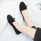paire de mocassins noirs portée avec un pantalon noir, vue jambes croisées