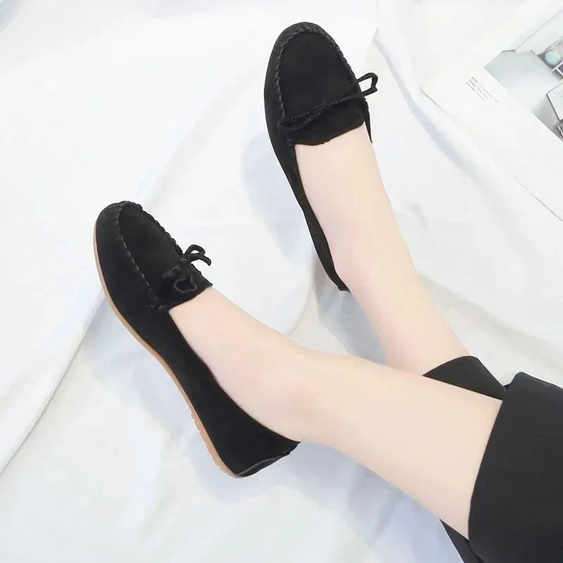 paire de mocassins noirs portée avec un pantalon noir, vue jambes croisées