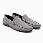 paire de mocassins gris posée sur fond blanc, vue de trois quarts