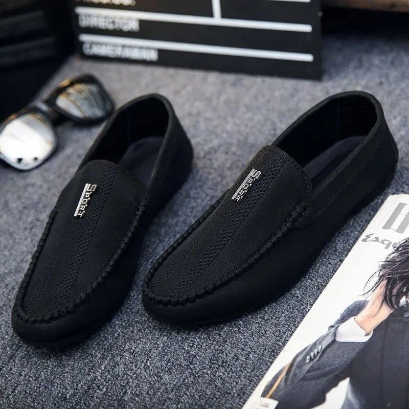 paire de mocassins noirs posée sur un tapis avec accessoires lifestyle autour