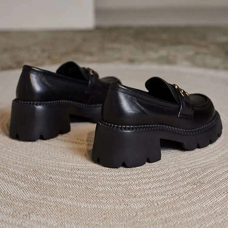 Paire de mocassins noirs à talons hauts vue de dos sur un tapis beige