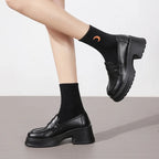 Paire de mocassins noirs portée, pied croisé, chaussettes noires avec motif lune