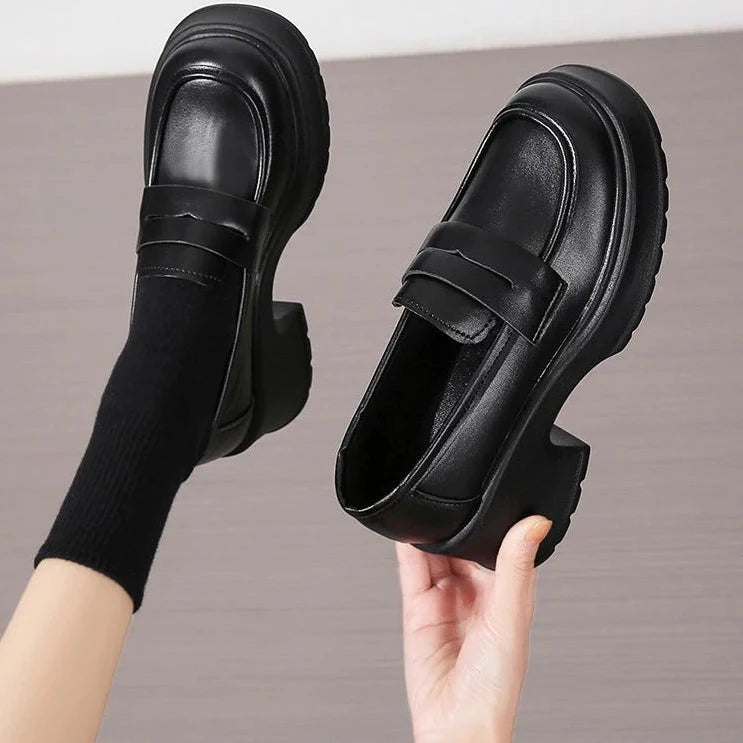Chaussure noire portée à la main et jambe levée avec chaussette noire
