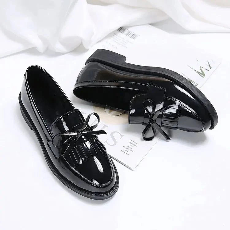 deux mocassins noirs, l’un couché, l’autre debout, sur fond blanc