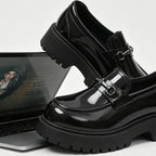 paire de mocassins noirs vernis posée sur un ordinateur portable, côté brillant visible