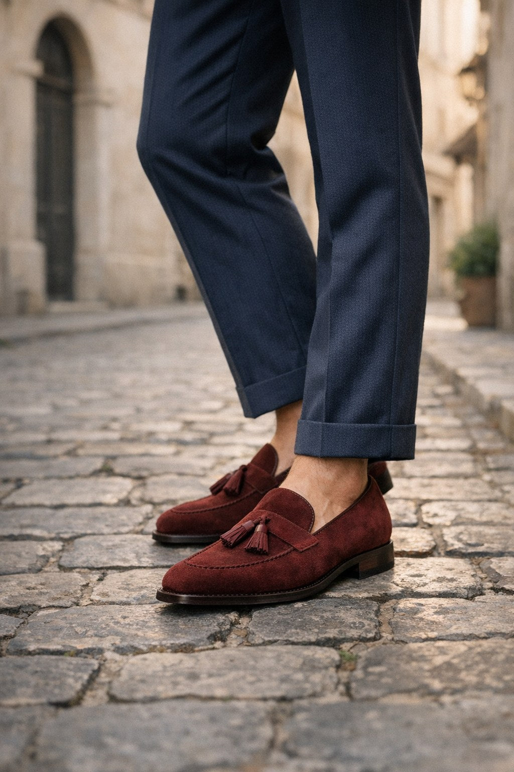 Mocassins homme à glands en daim bordeaux portés sur des pavés