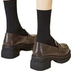 Loafers marron vus de dos, portés avec des chaussettes noires montantes