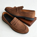 paire de mocassins marron posée à côté d'un portefeuille marron