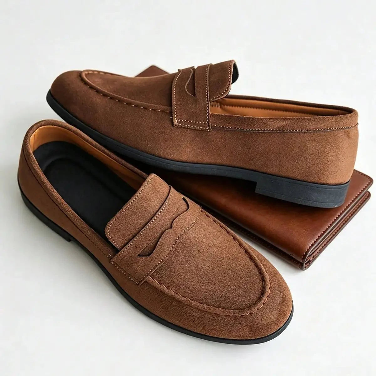 paire de mocassins marron posée à côté d'un portefeuille marron