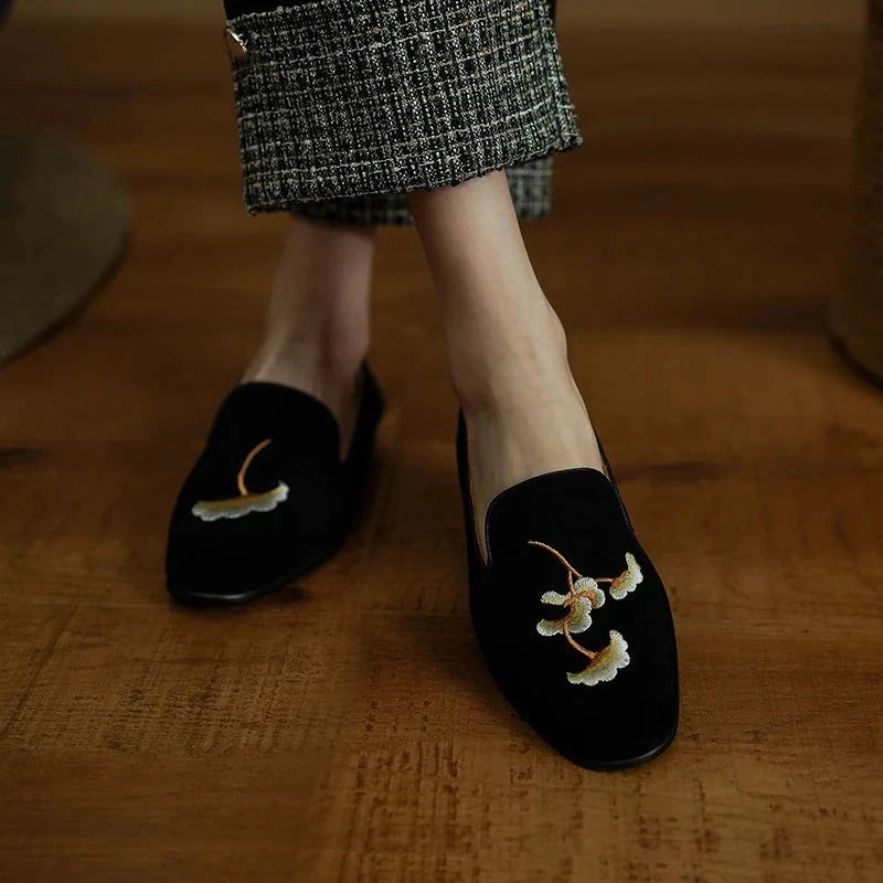 vue de face de deux mocassins noirs brodés aux pieds d'une personne