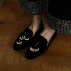 une paire de mocassins noirs brodés portée avec un pantalon à carreaux
