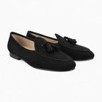 Slippers homme à pompons noirs, paire vue de trois quarts sur fond gris clair
